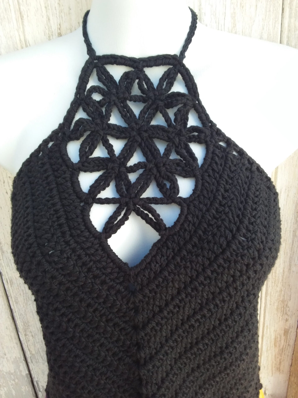 A black crochet halter crop top with picot edging paired with a bright orange skirt