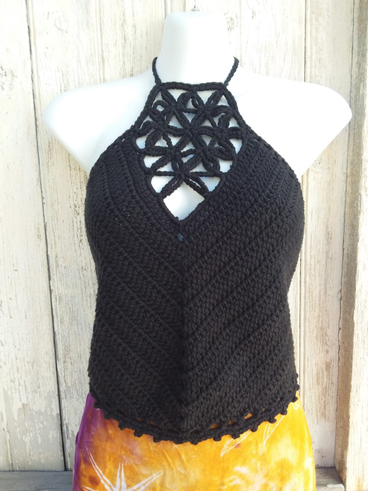 A black crochet halter top with picot edging paired with a bright orange skirt
