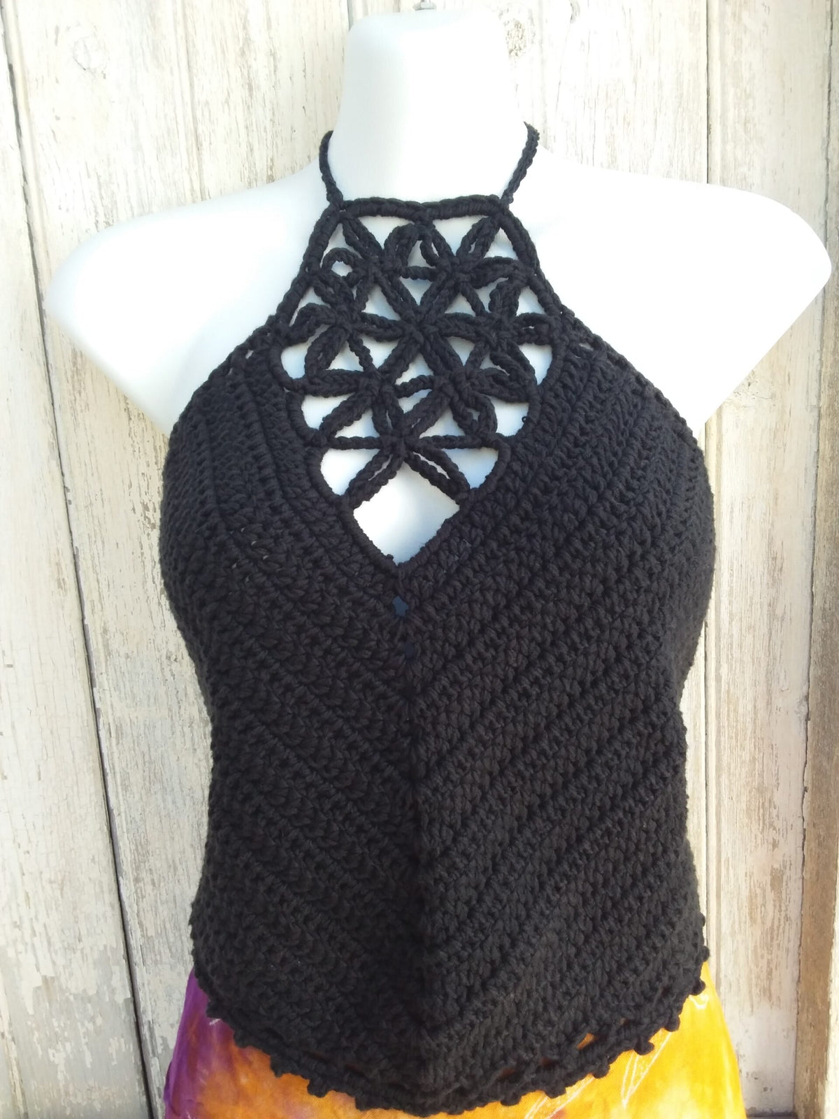 a black crochet crop top halter on a mannequin.