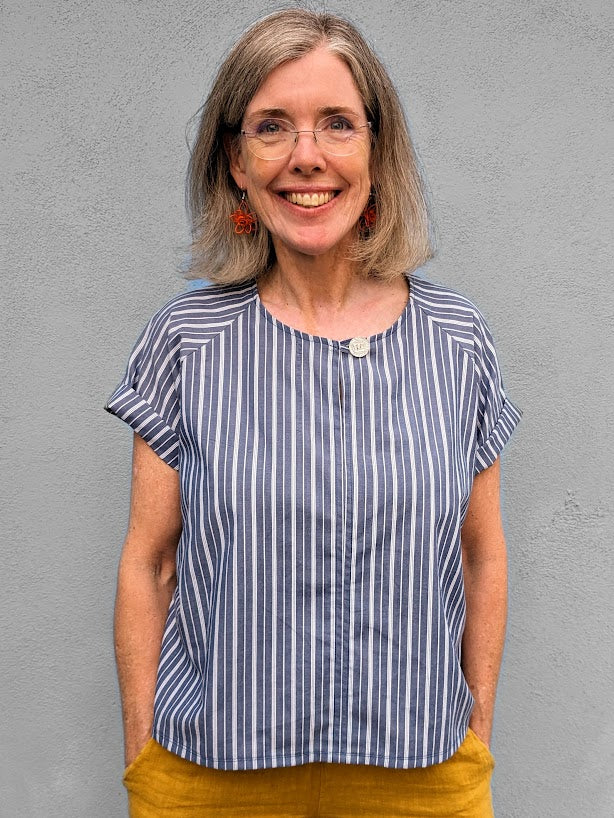 A woman wearing a blue striped top and yellow pants.
