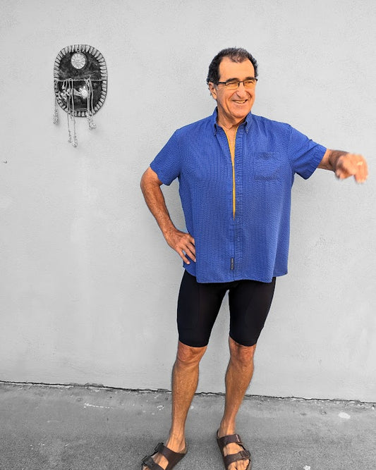 A man in a blue shirt standing next to a wall.