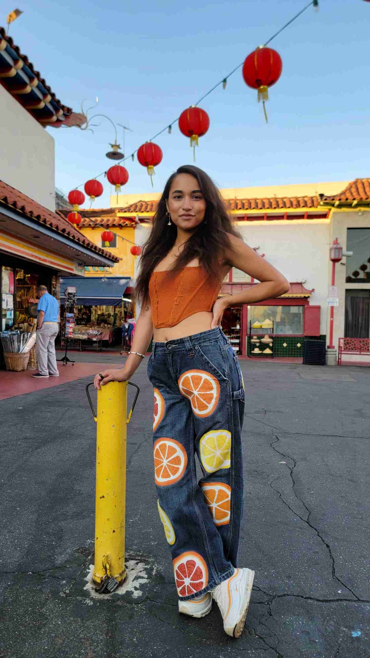 a woman standing next to a pole with oranges on it.