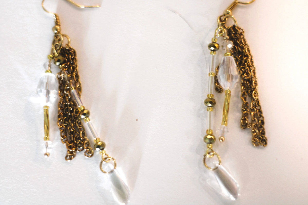A pair of gold tassel earrings with clear crystals.