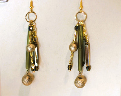 A pair of earrings with gold and green beads.