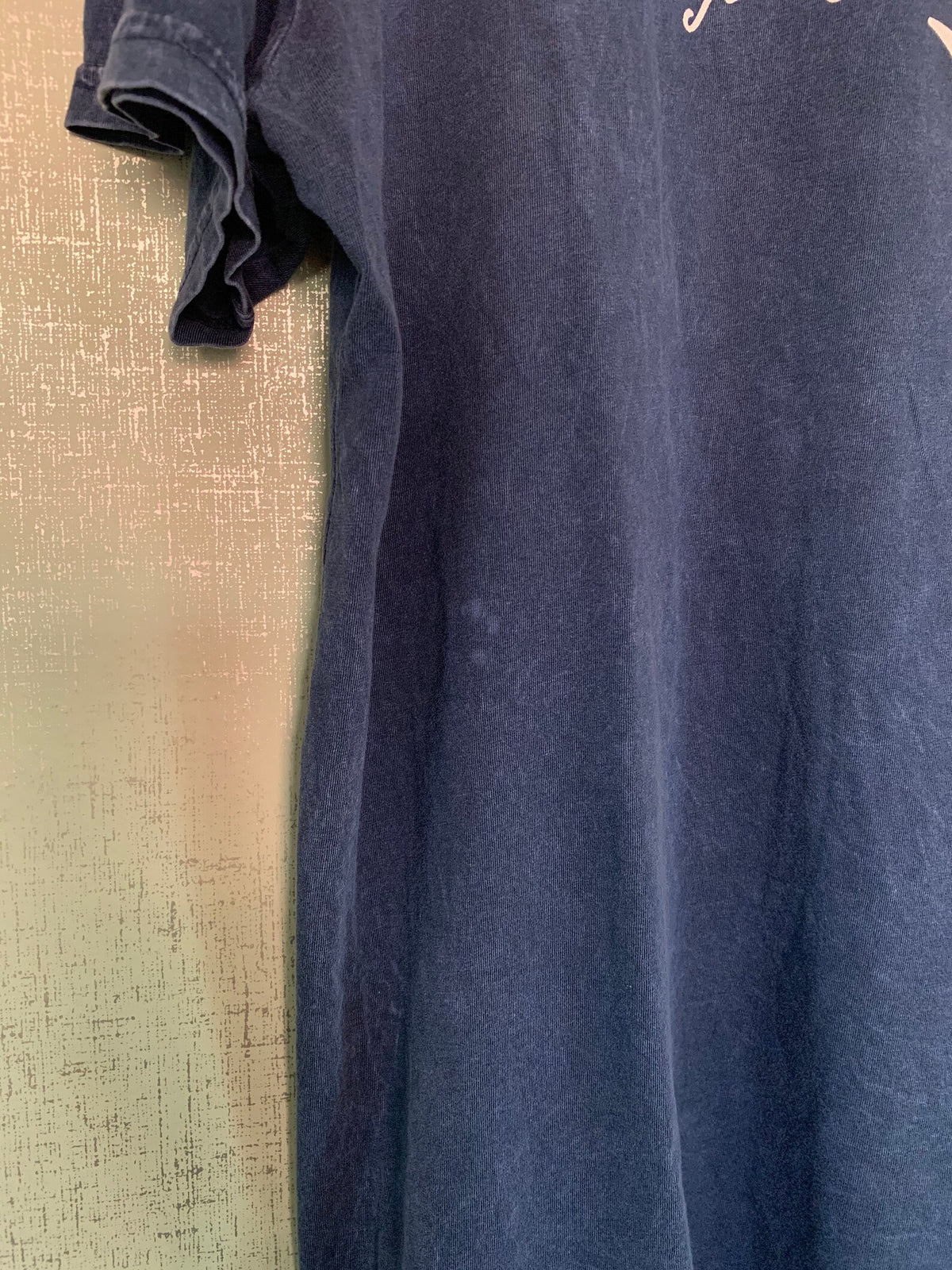 A blue t - shirt hanging on a wall.