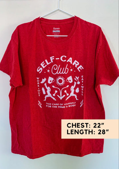 A red t - shirt that says self care club.