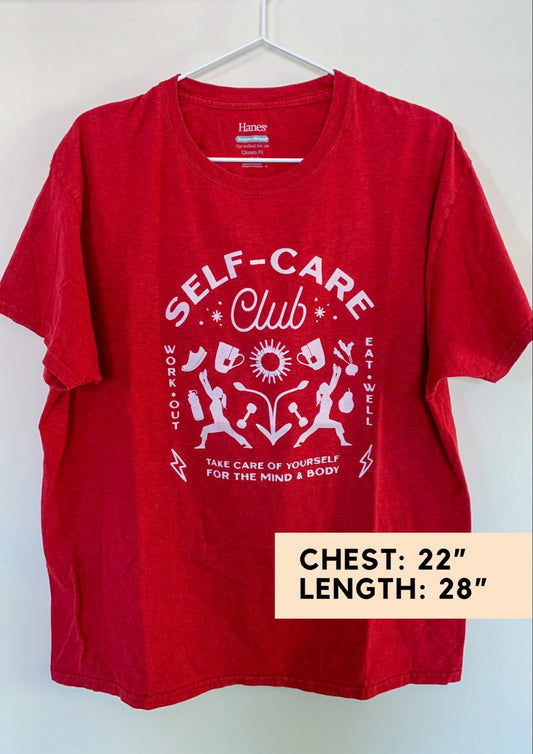 A red t - shirt that says self care club.