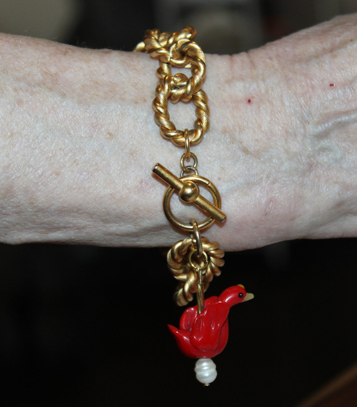 A woman wearing a bracelet with a red bird on it.