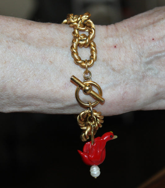 A woman wearing a bracelet with a red bird on it.