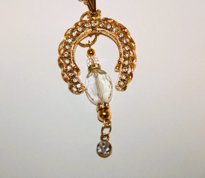 A gold horseshoe necklace with a crystal drop.