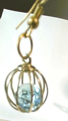 Close up of one of the caged blue bead earrings hanging