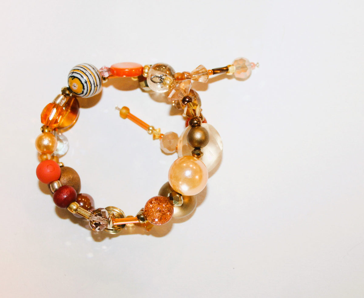 A bracelet with orange, brown, and gold beads.