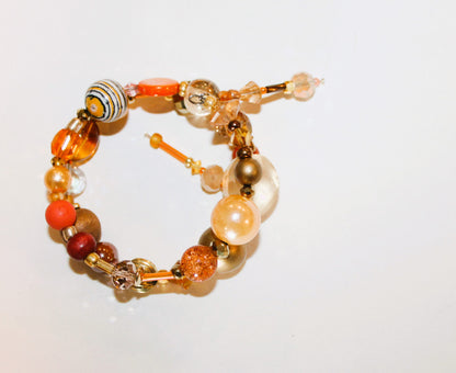A bracelet with orange, brown, and gold beads.