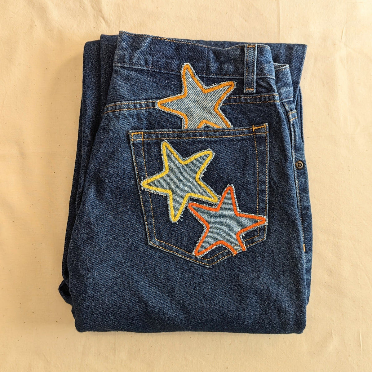 A pair of jeans with stars embroidered on them.