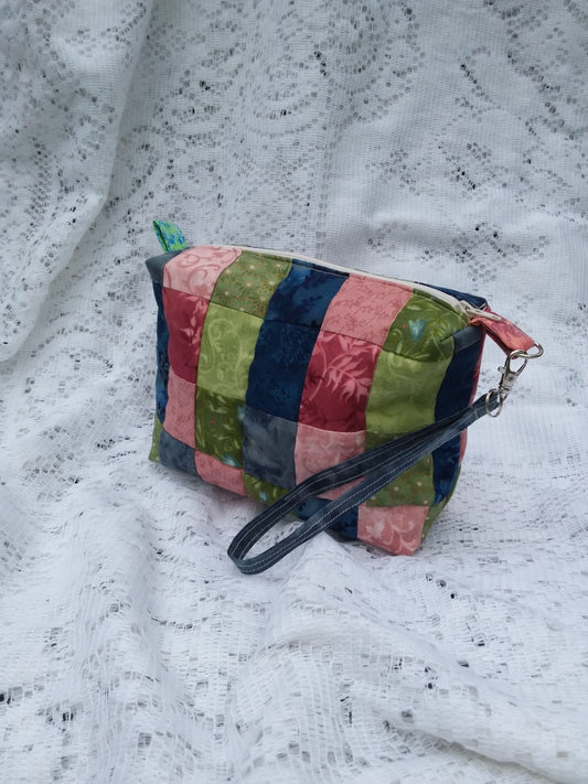 A colorful quilted pouch with a strap.