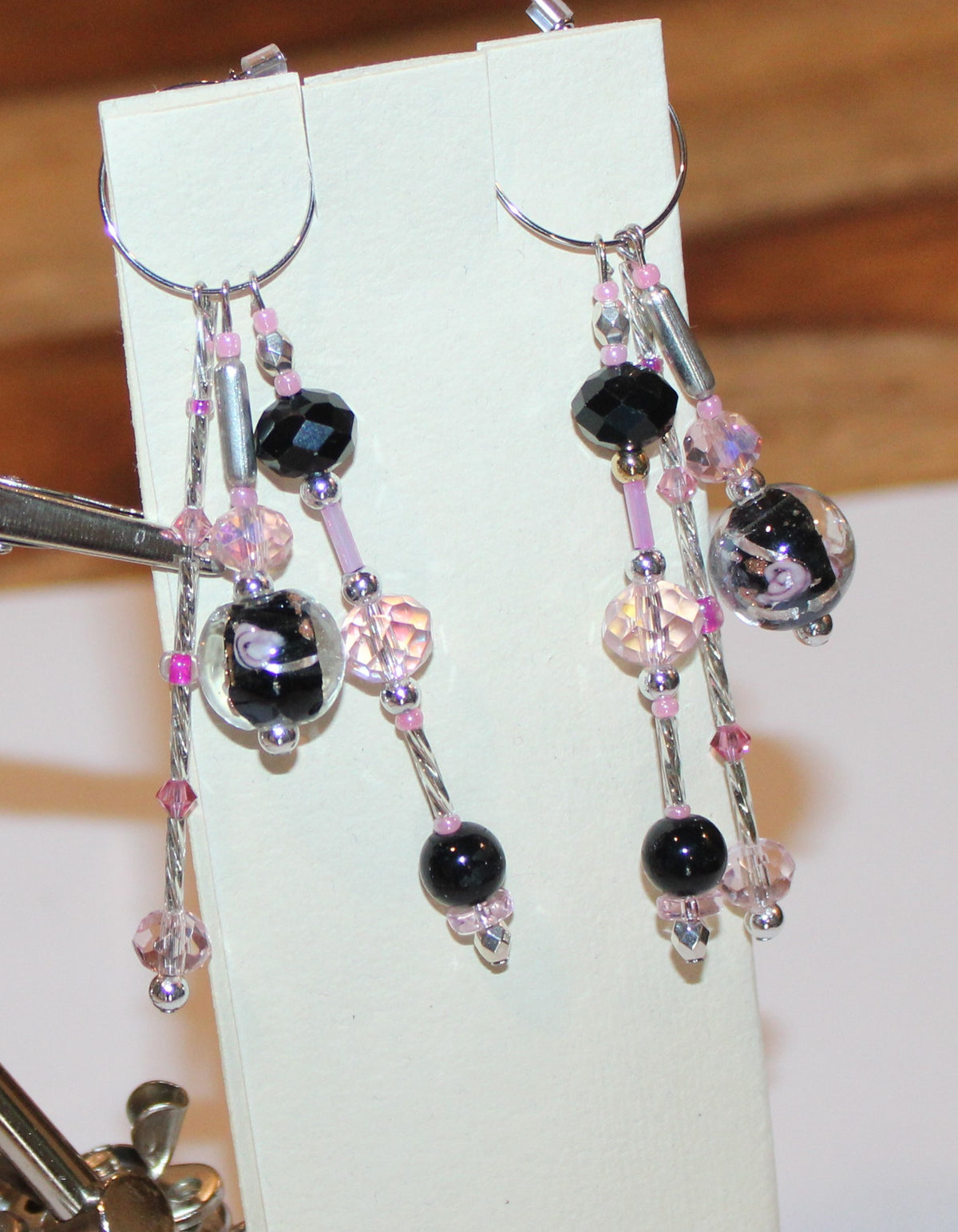 A pair of earrings with black and pink beads.