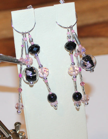 A pair of earrings with black and pink beads.