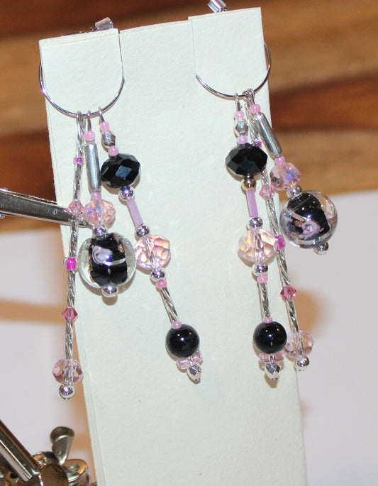 A pair of earrings with black and pink beads.