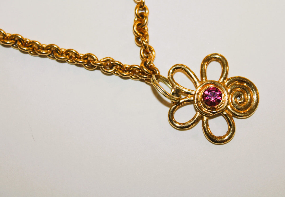 A gold necklace with a pink stone.