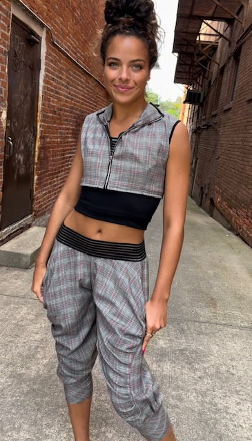 A young woman wearing a plaid hoodie and joggers.