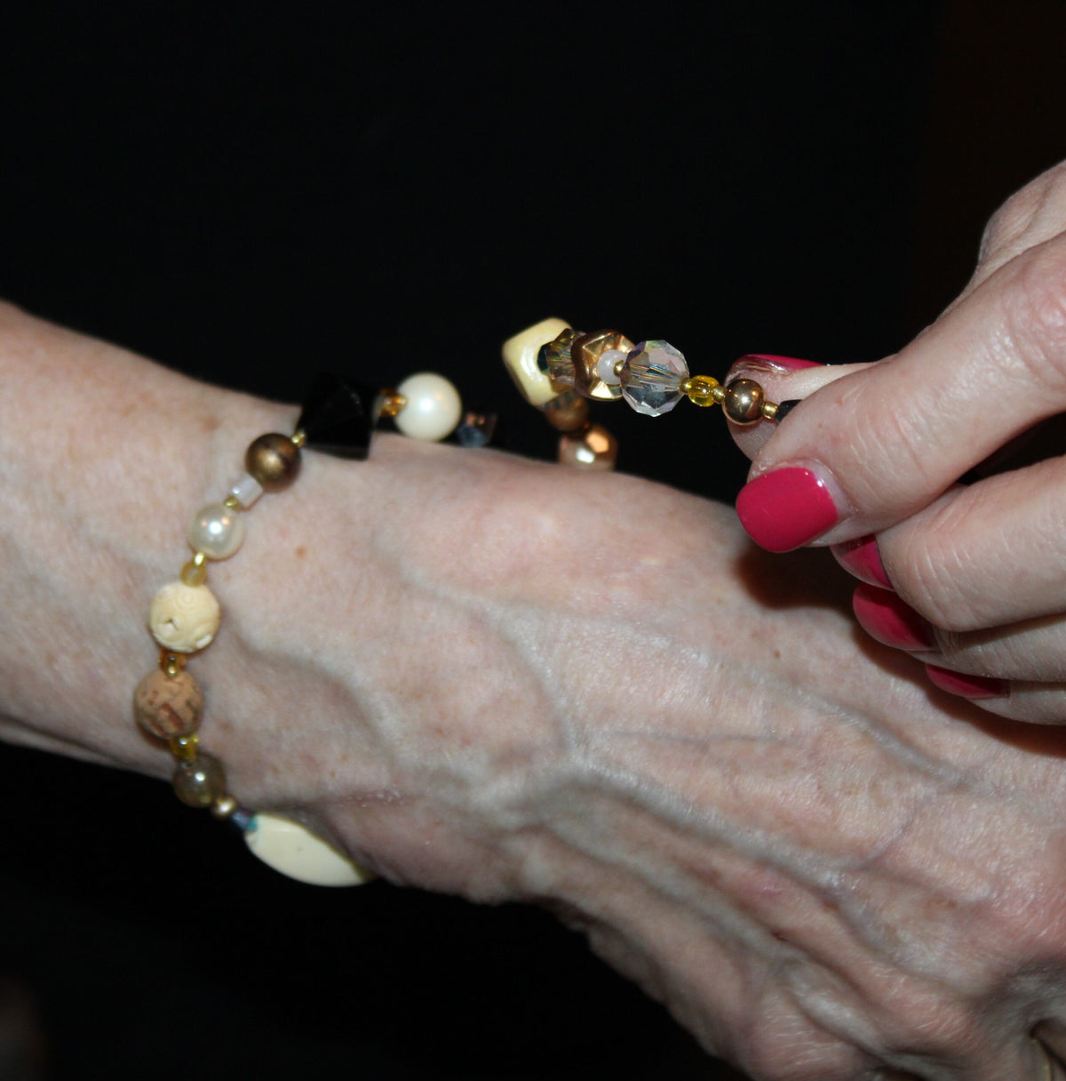 View of putting on the first wrap of the ivory and black tone beaded bracelet