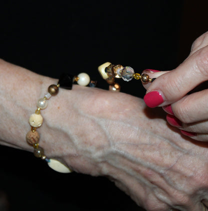 View of putting on the first wrap of the ivory and black tone beaded bracelet