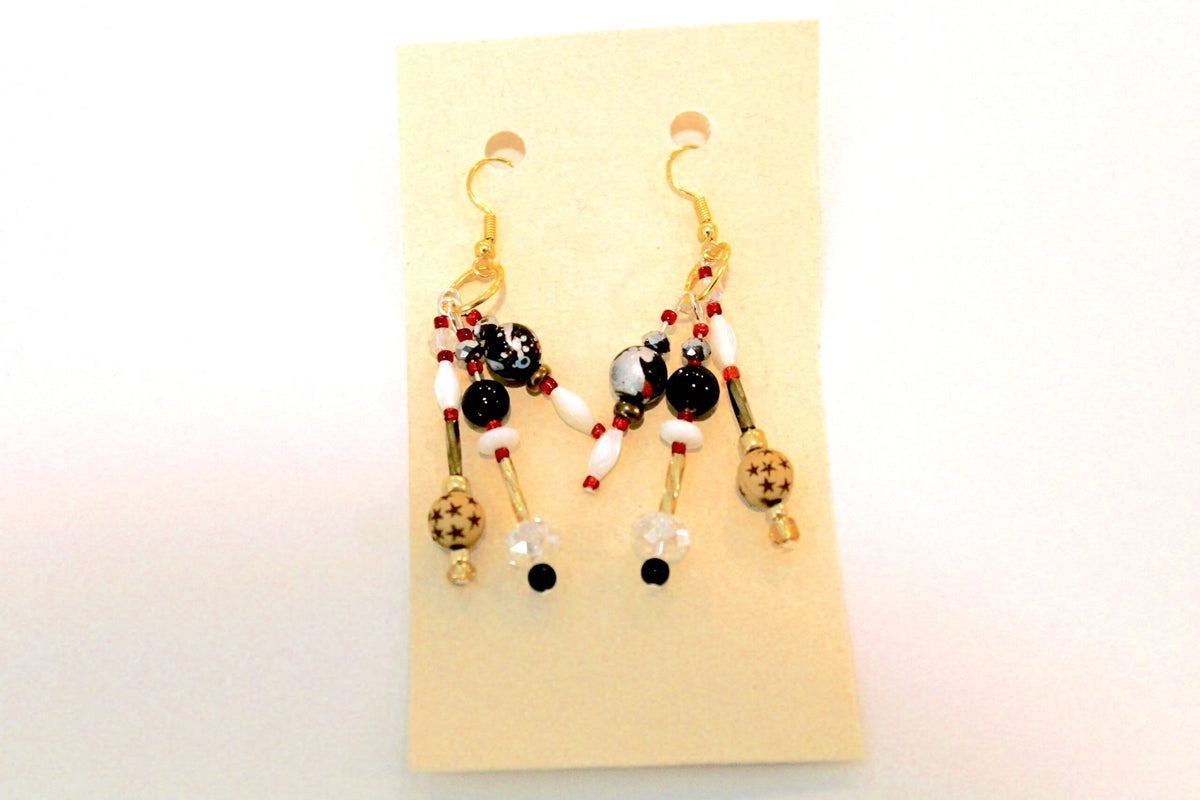 A pair of earrings with red, black and white beads.
