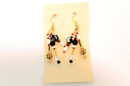 A pair of earrings with red, black and white beads.