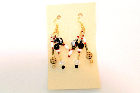 A pair of earrings with red, black and white beads.