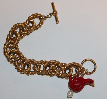A gold chain bracelet with a red bird and pearl.