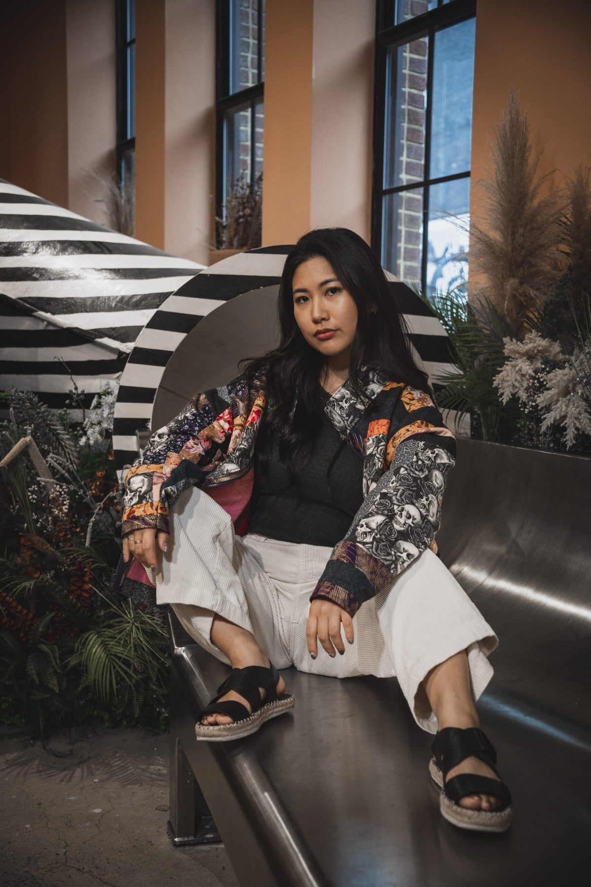 A woman sitting on a bench in front of plants.