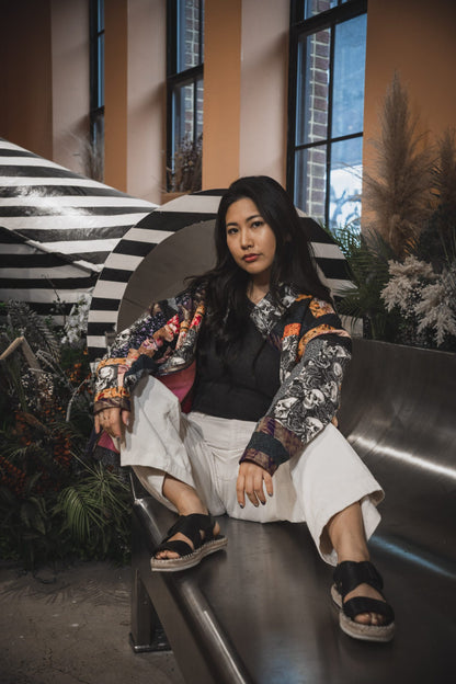 A woman sitting on a bench in front of plants.