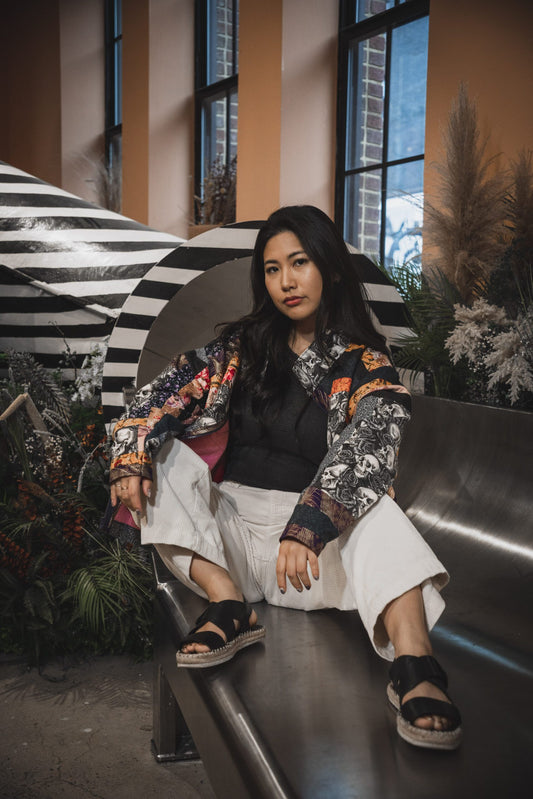 A woman sitting on a bench in front of plants.