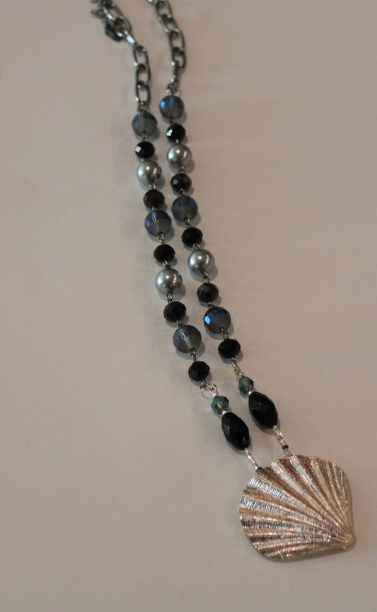 A necklace with a silver shell and black beads.