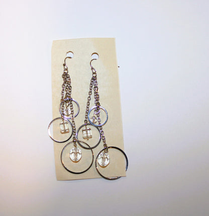 A pair of silver dangling earrings on a card.