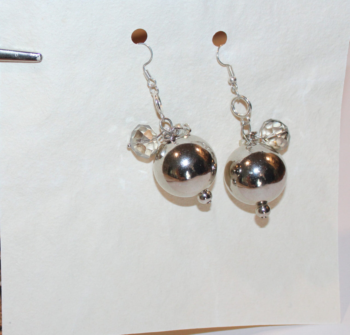 A pair of silver earrings on a piece of paper.