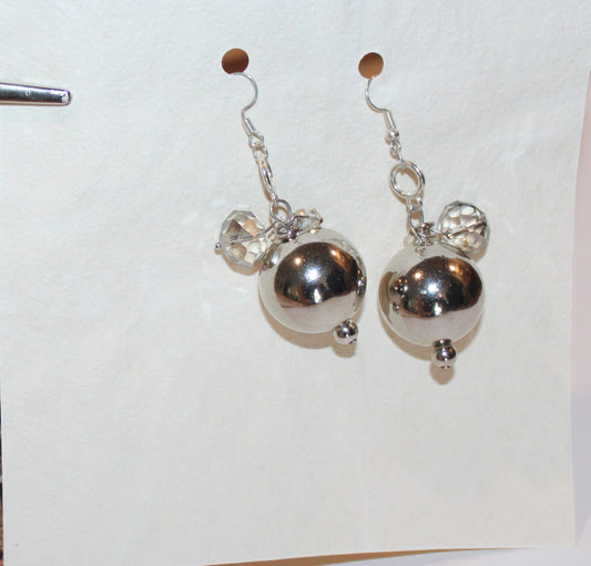 A pair of silver earrings on a piece of paper.