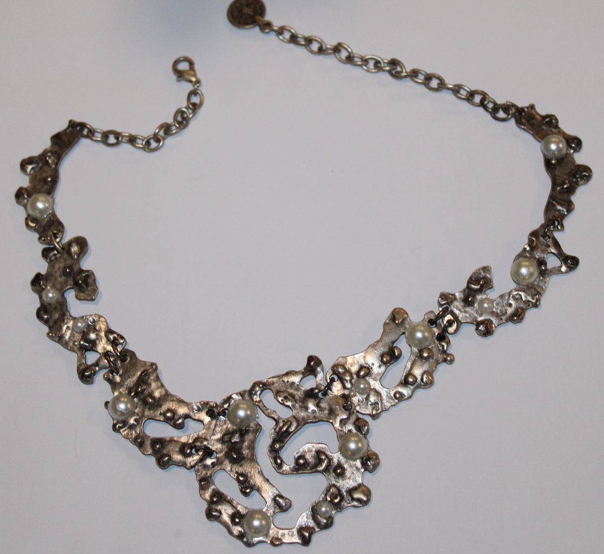 segmented silver tone necklace on a white surface