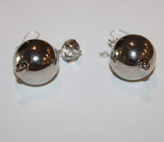 A pair of silver ball earrings on a white surface.