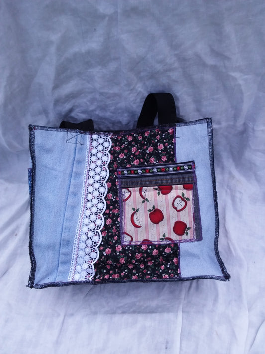 An upcycled denim tote bag with a patchwork pattern and pocket
