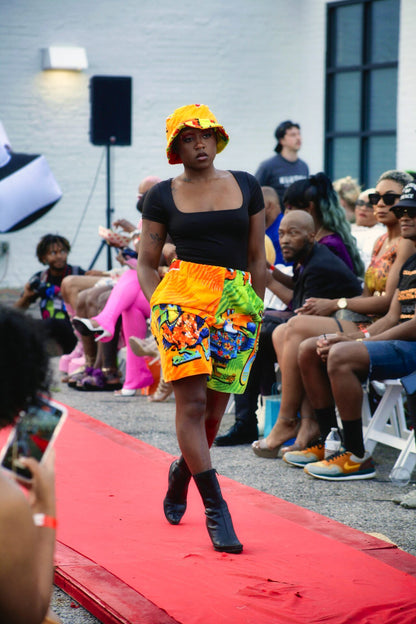 a black woman walking down the runway at a fashion show.