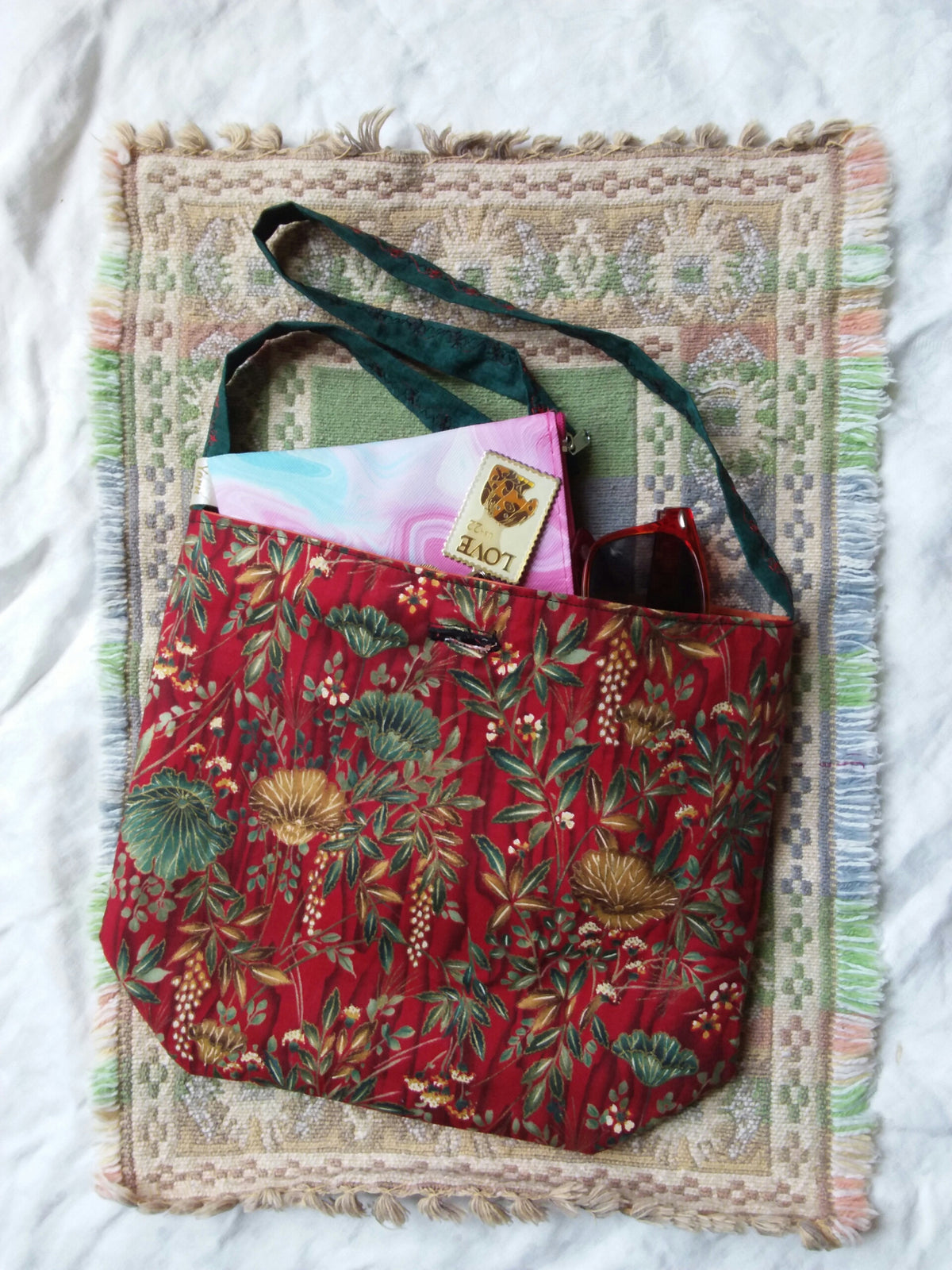 Elegant oriental poppies in gold and green adorn a red fabric hand bag