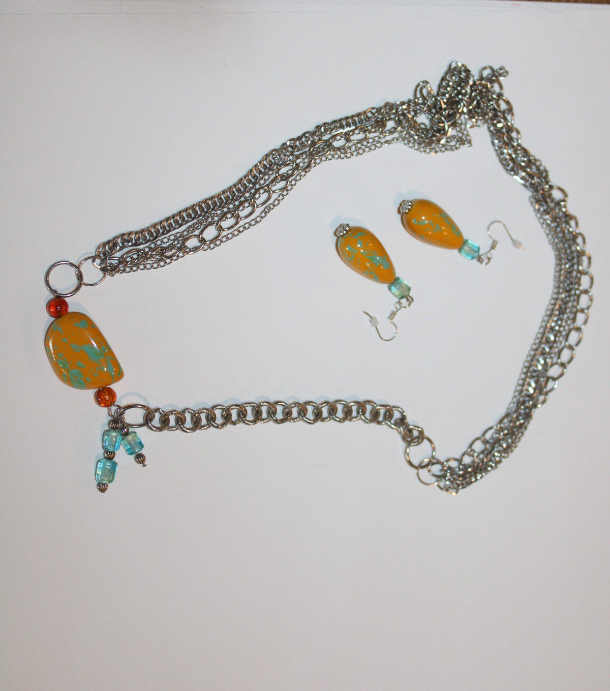 A necklace and earrings are sitting on a table.
