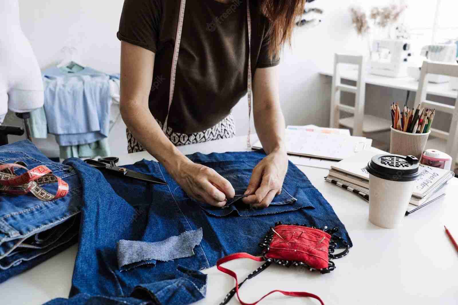 a woman is working on a pair of jeans.