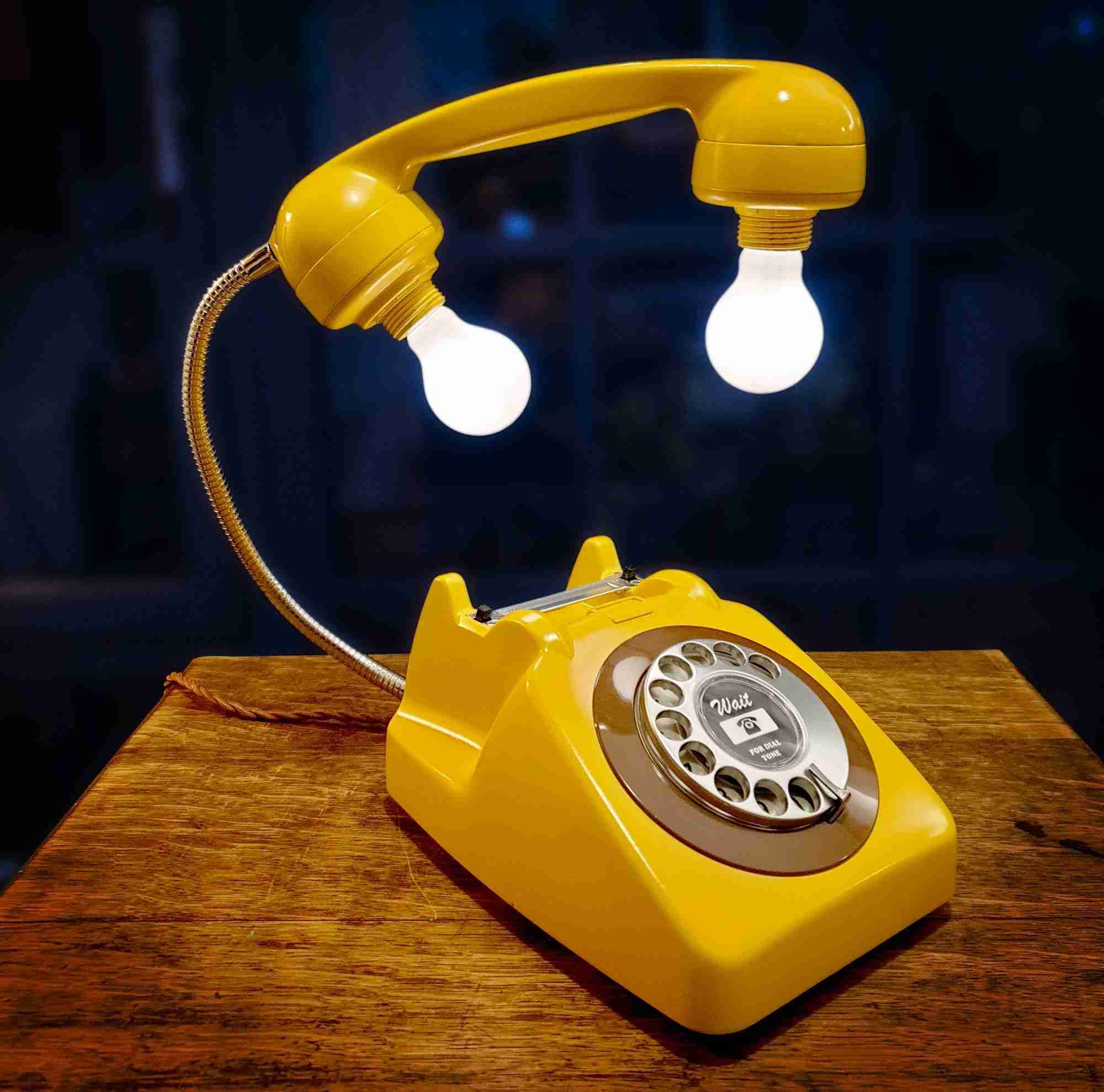 a yellow telephone sitting on top of a wooden table.