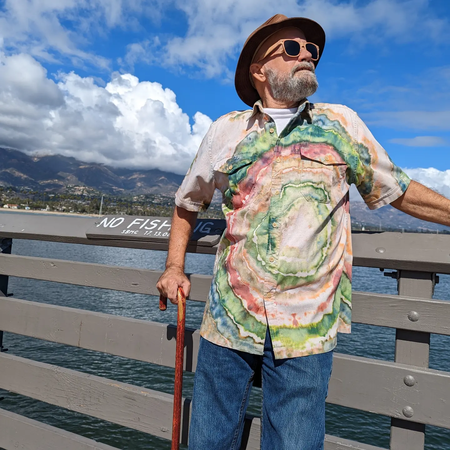 a man standing on a pier holding a cane.