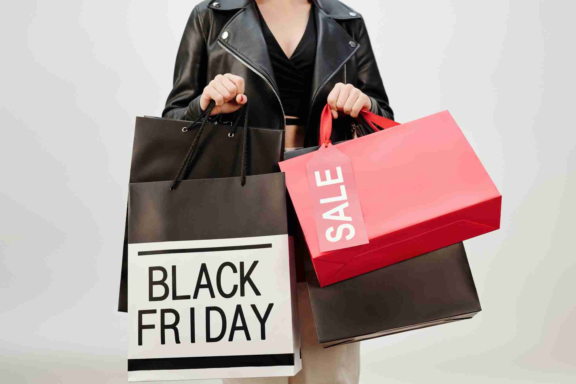 a woman holding two shopping bags and a black friday sign.
