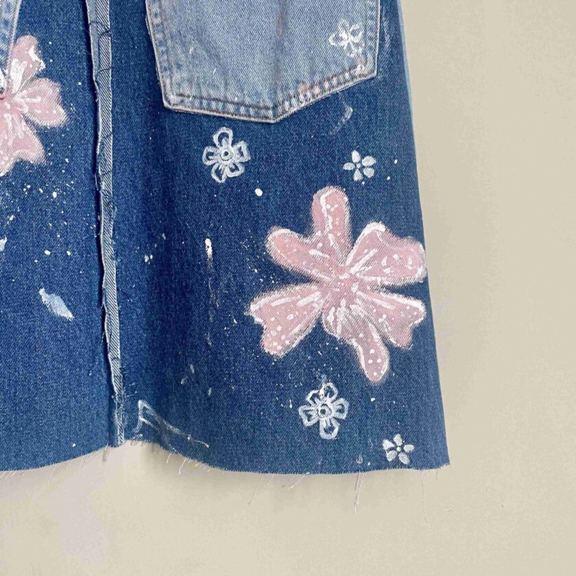 a pair of jeans with pink flowers painted on them.