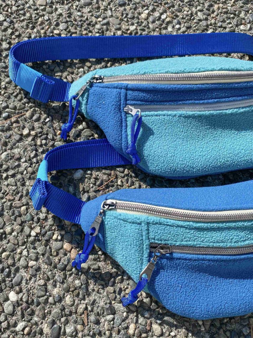 a pair of blue fanny bags sitting on top of a gravel road.