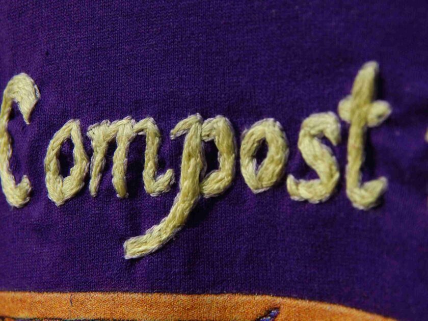a close up of a purple shirt with the word compost written on it.